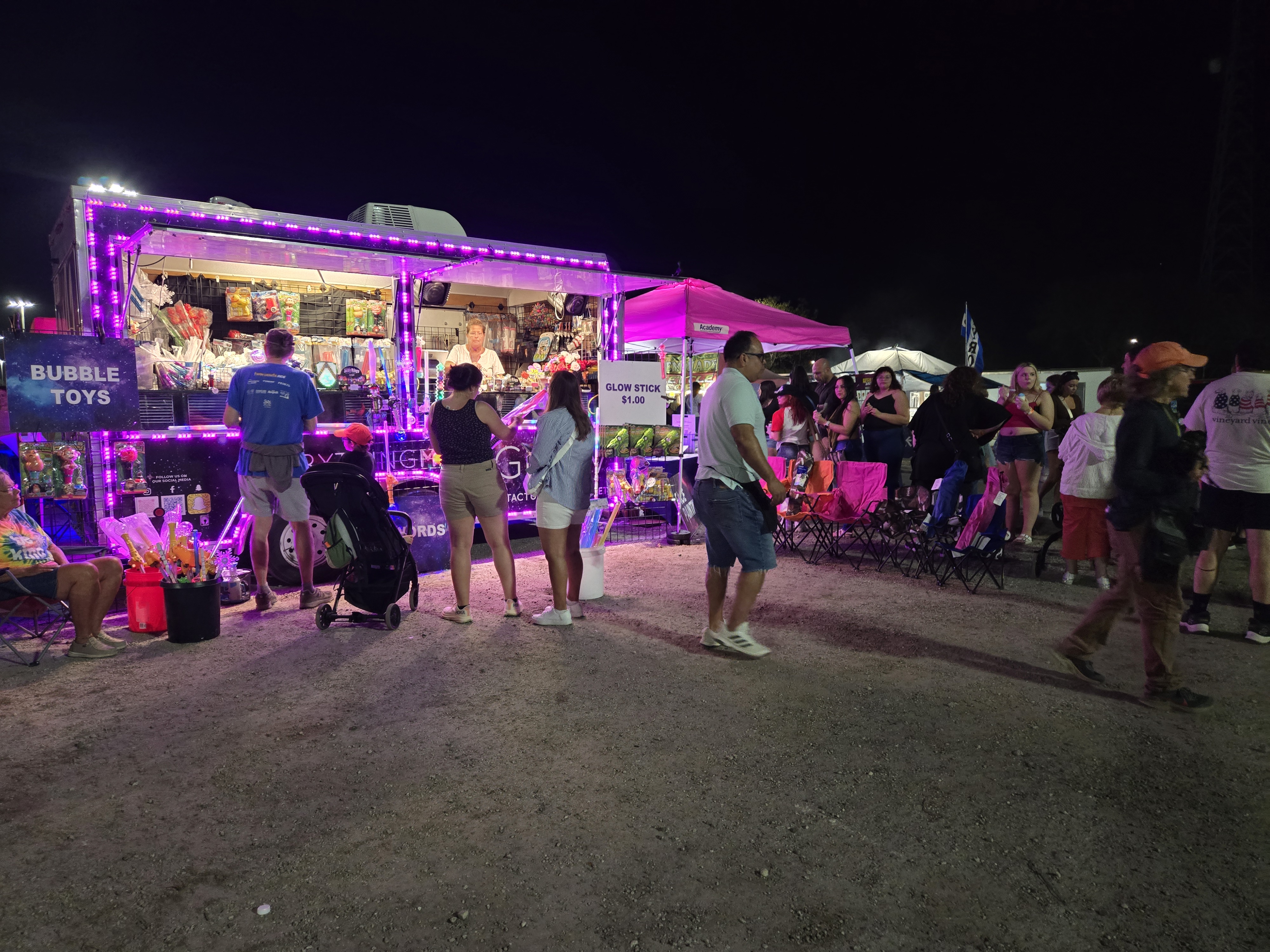 Our trailer and booth setup glowing purple at a busy nighttime event