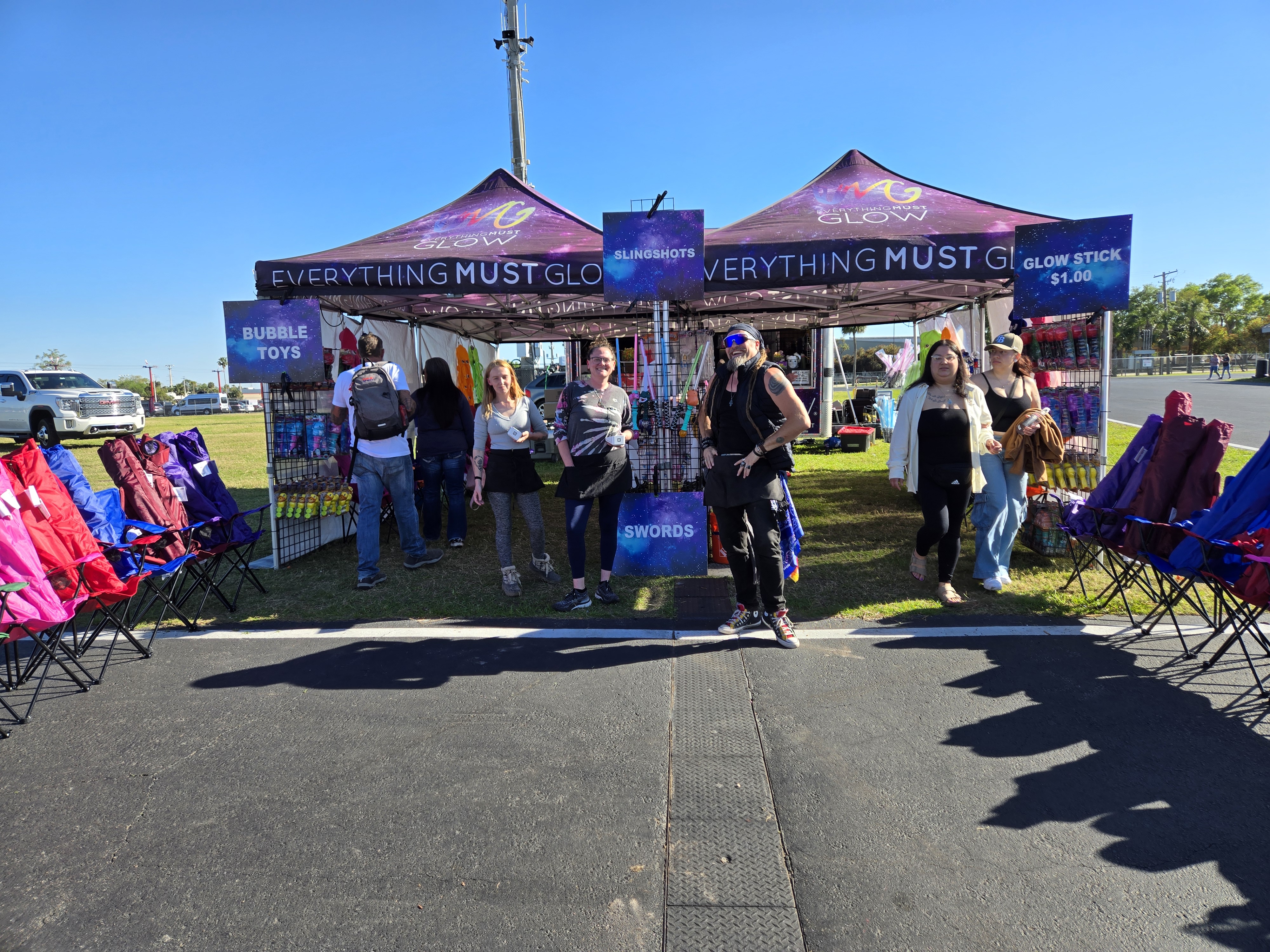 Bobby posted up in front of the double tent setup with camping chairs and bubble toy signs