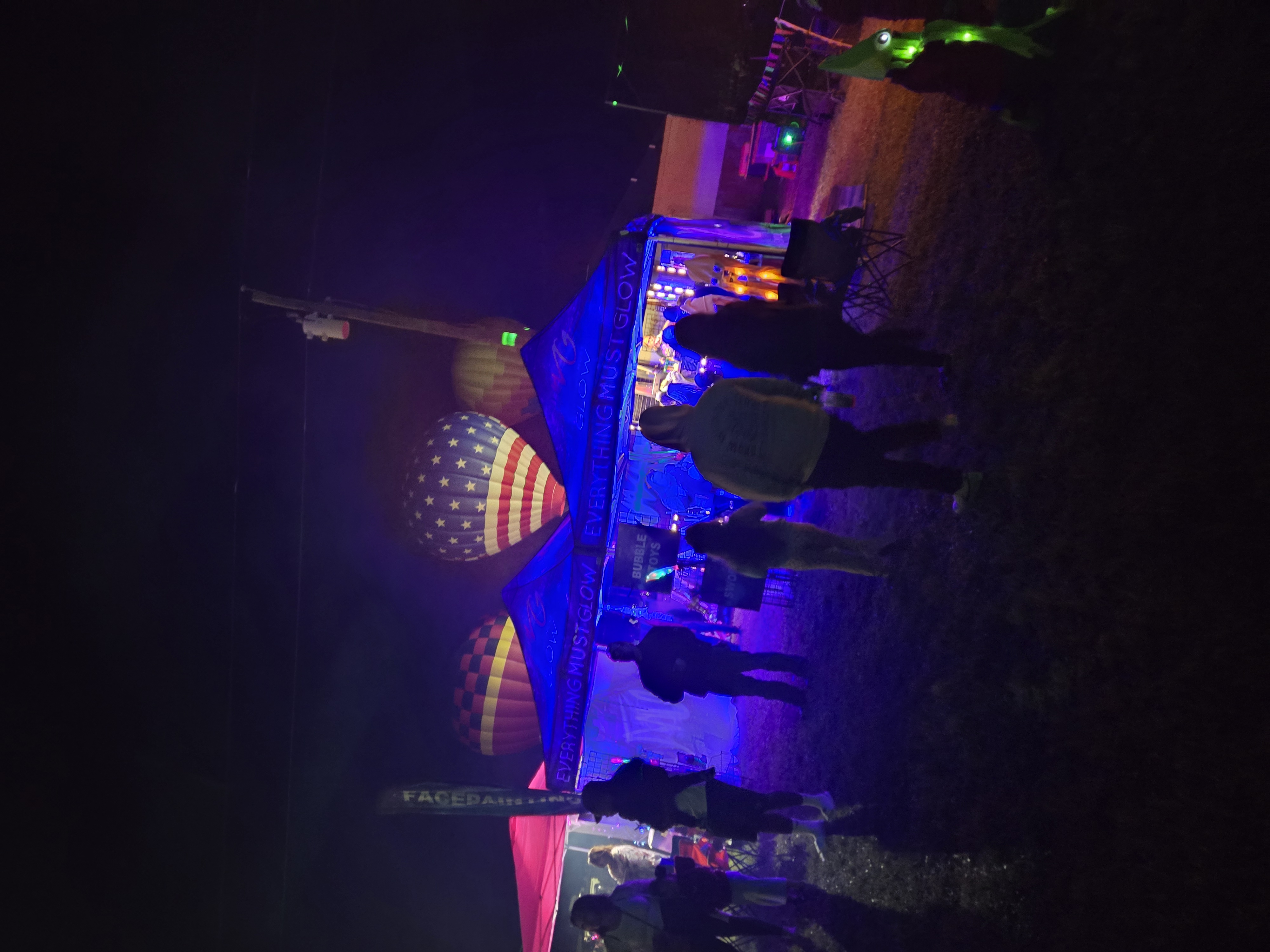 Our UV-lit booth glowing blue alongside hot air balloons and the American flag balloon