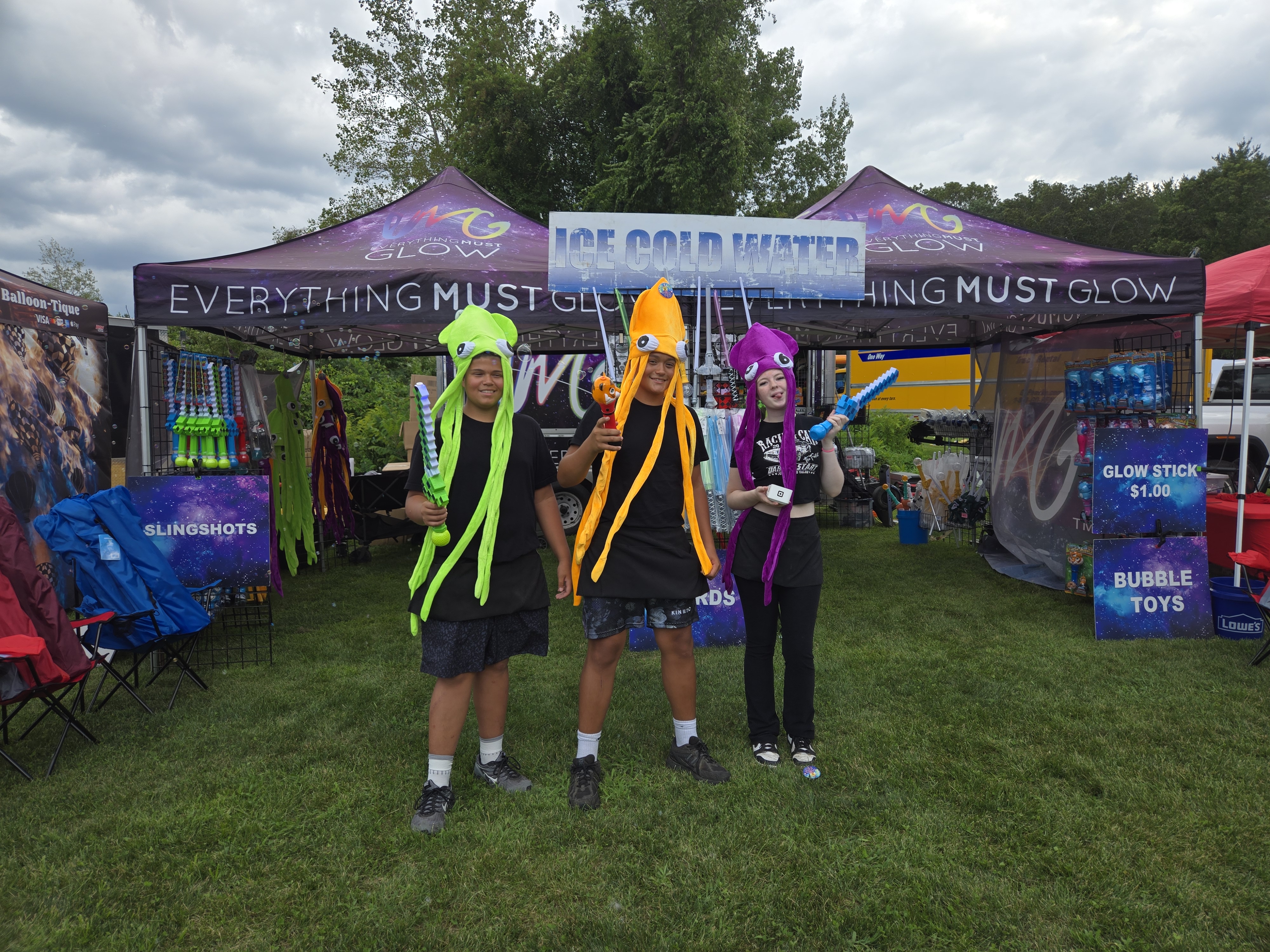 The crew rocking jellyfish hats in front of the booth — we don't just sell the fun, we live it