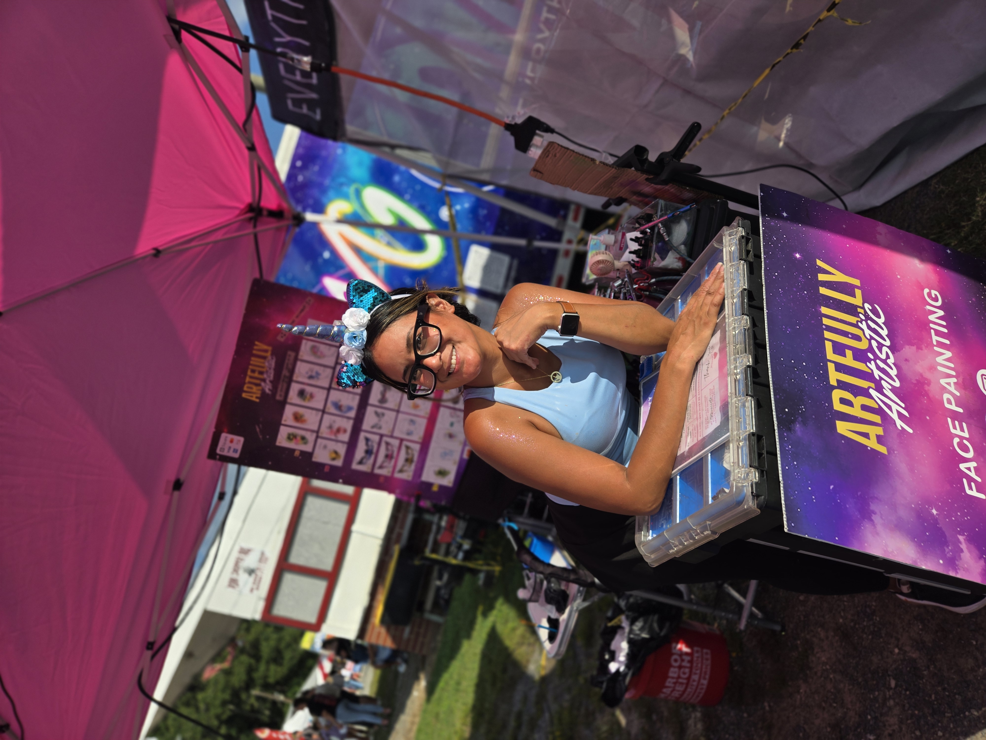 Our face painting partner Artfully Artistic smiling and set up next to the EMG booth