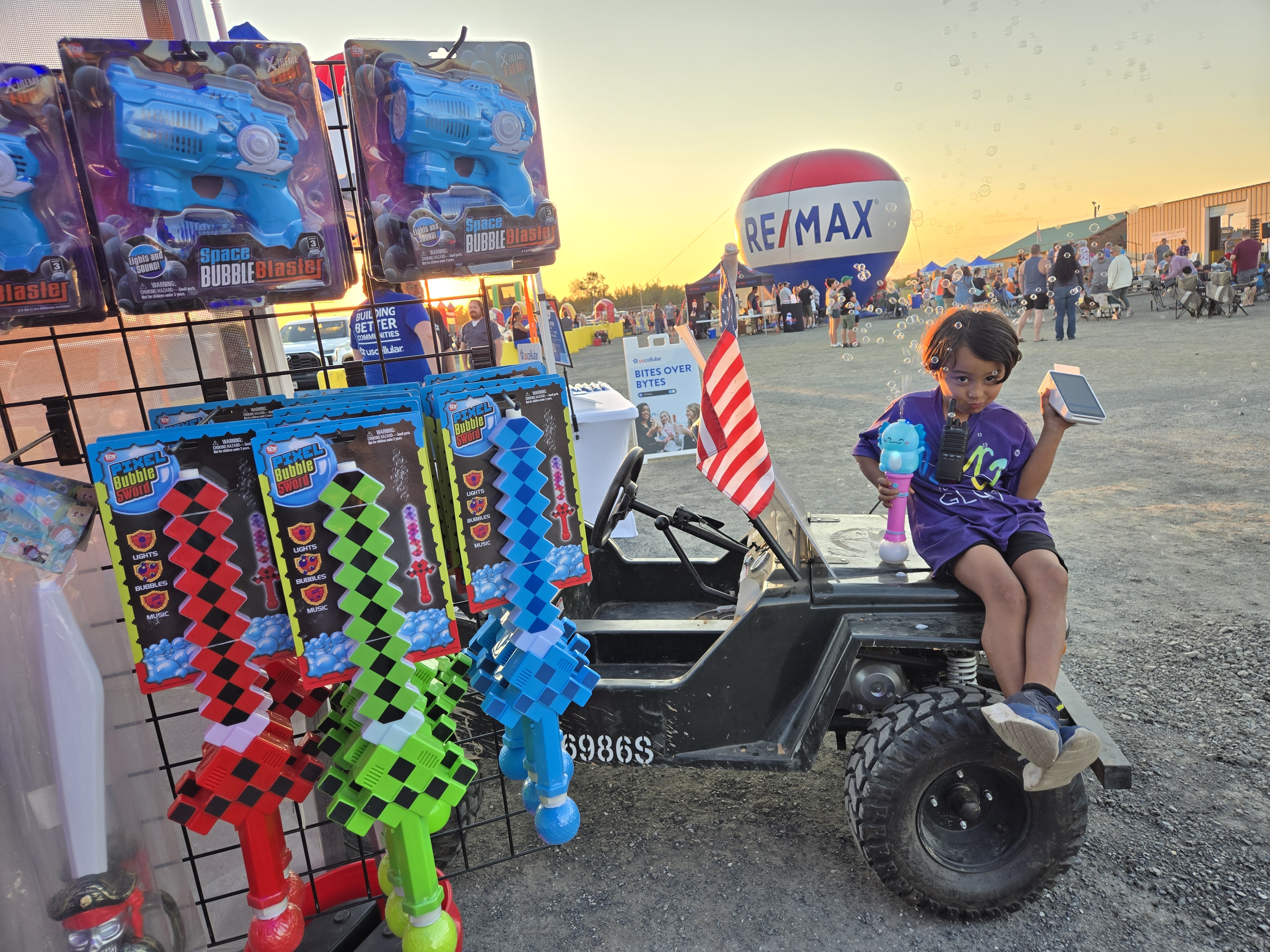 Our little one sitting on the jeep with pixel swords, RE/MAX balloon in the background