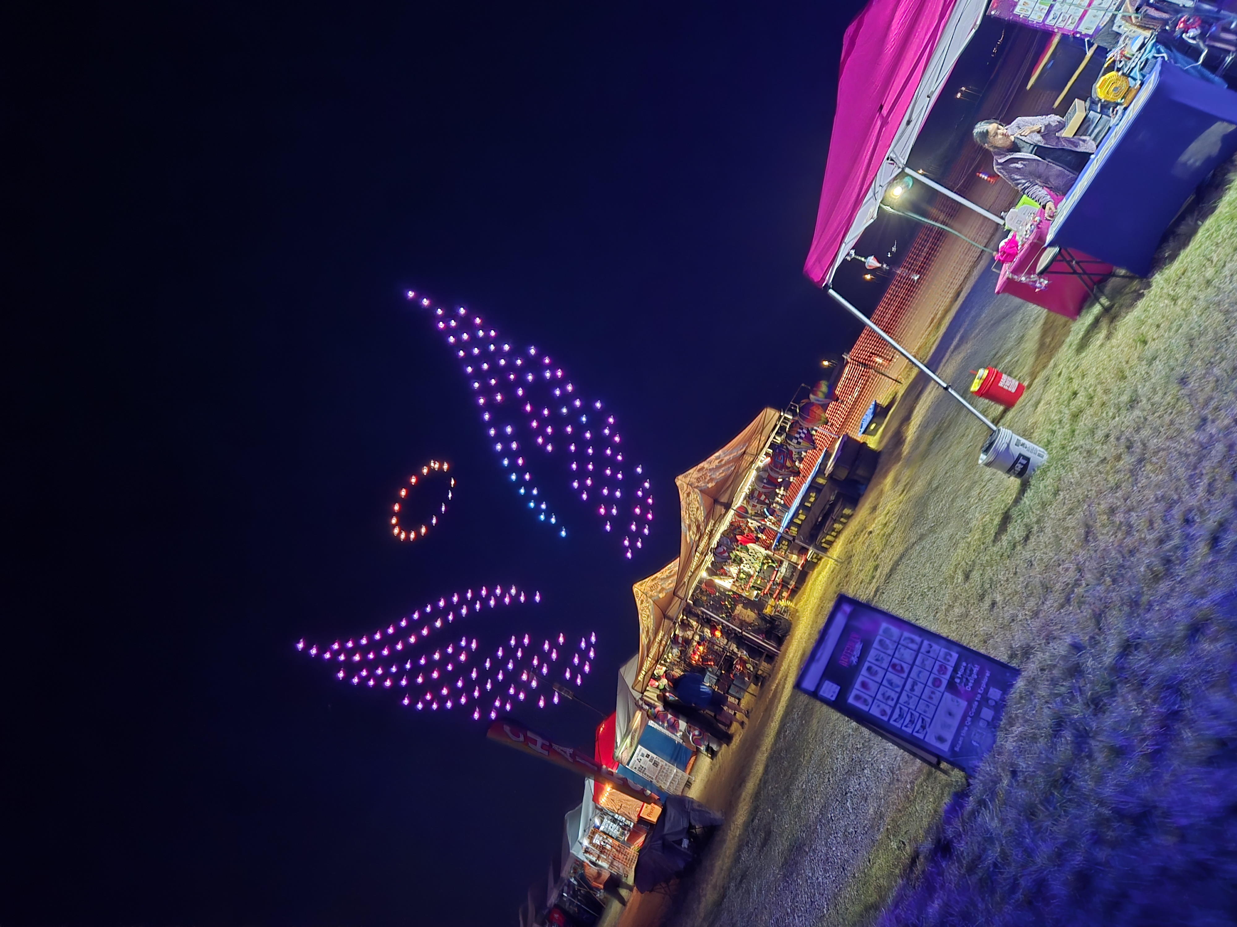 A drone light show creating a massive design in the sky above the festival
