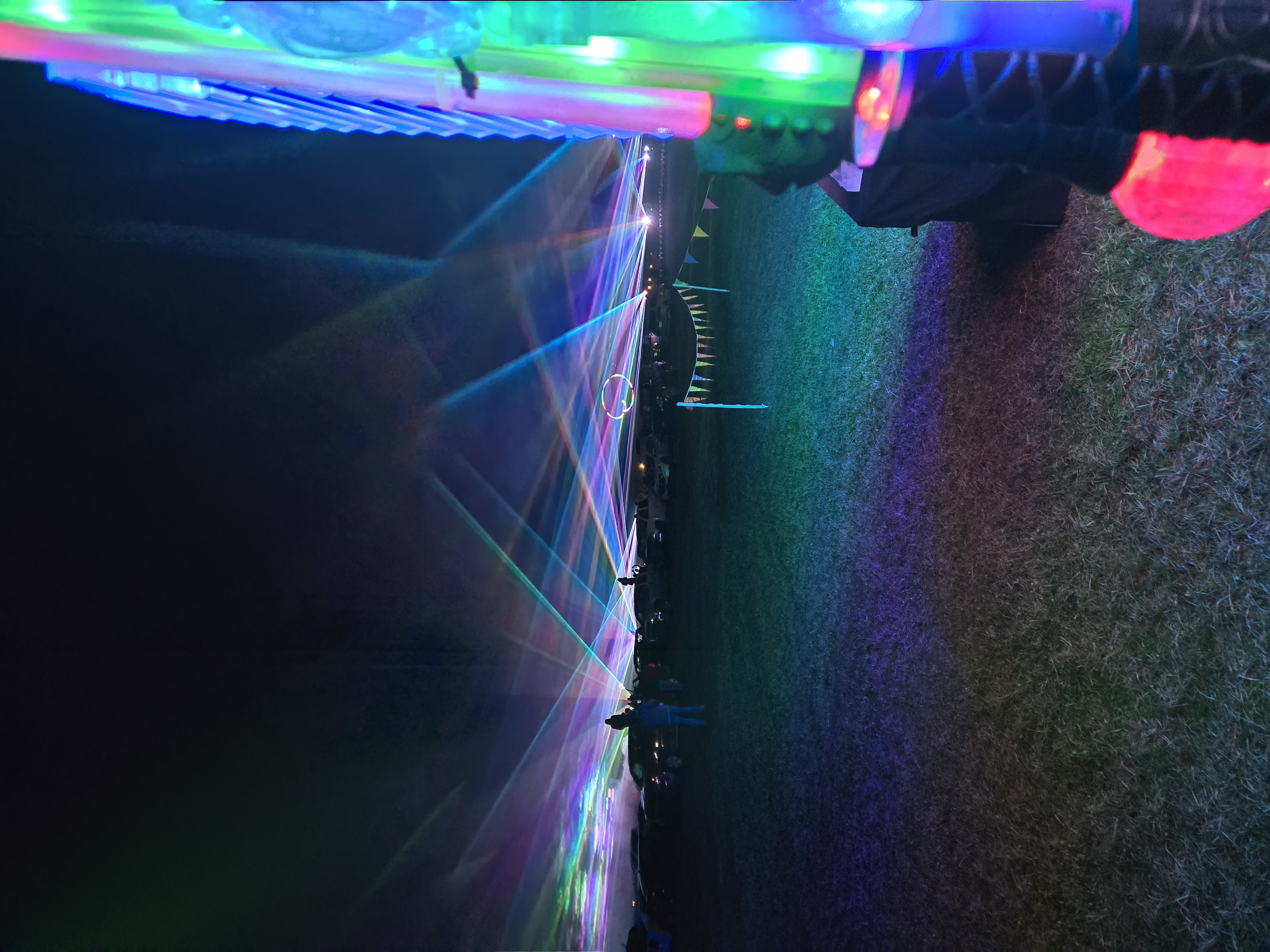 Multi-color laser beams shooting across the sky from our booth with glow products on display