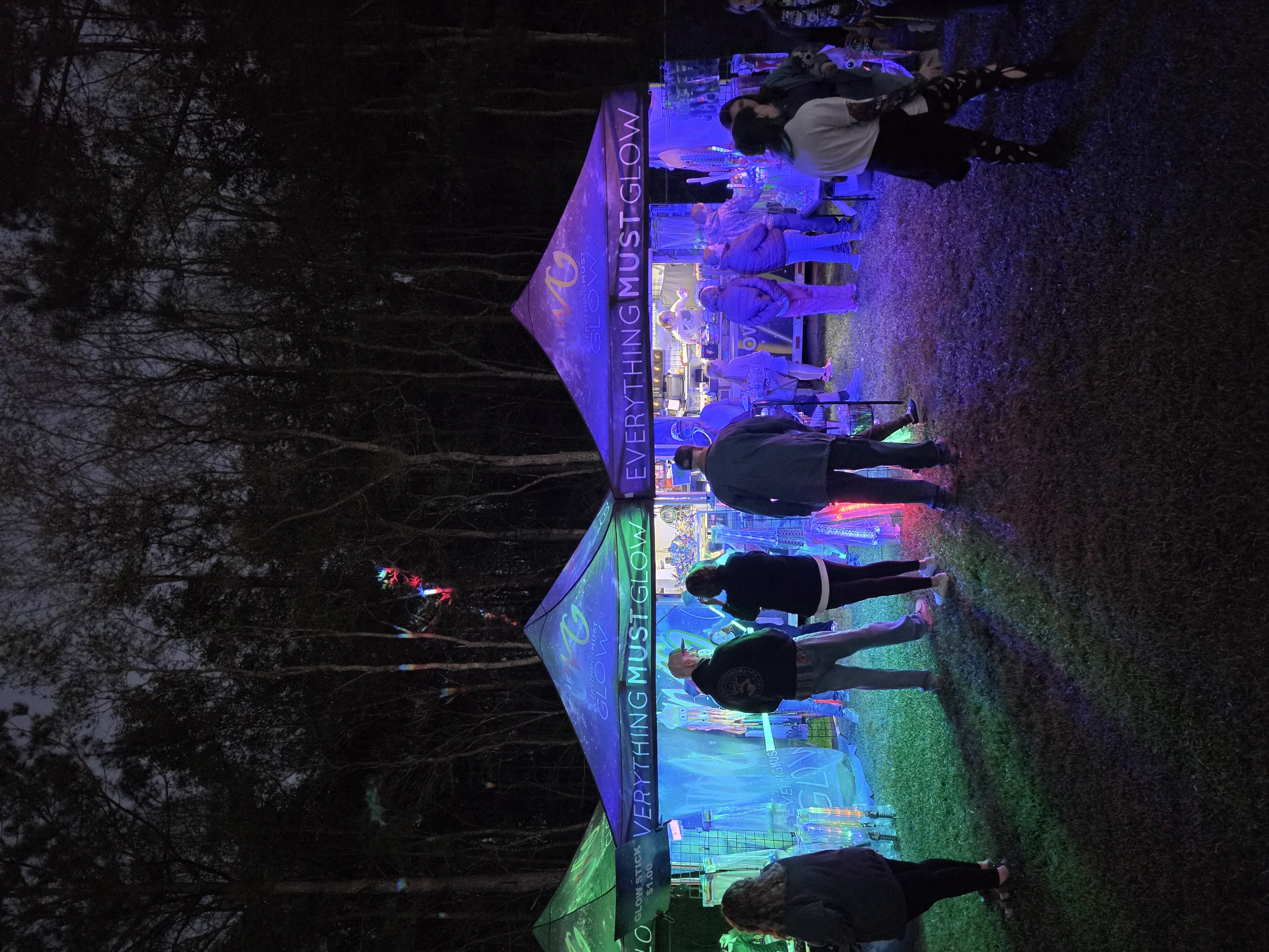 Customers browsing our UV-lit booth lined with glow sticks and LED toys