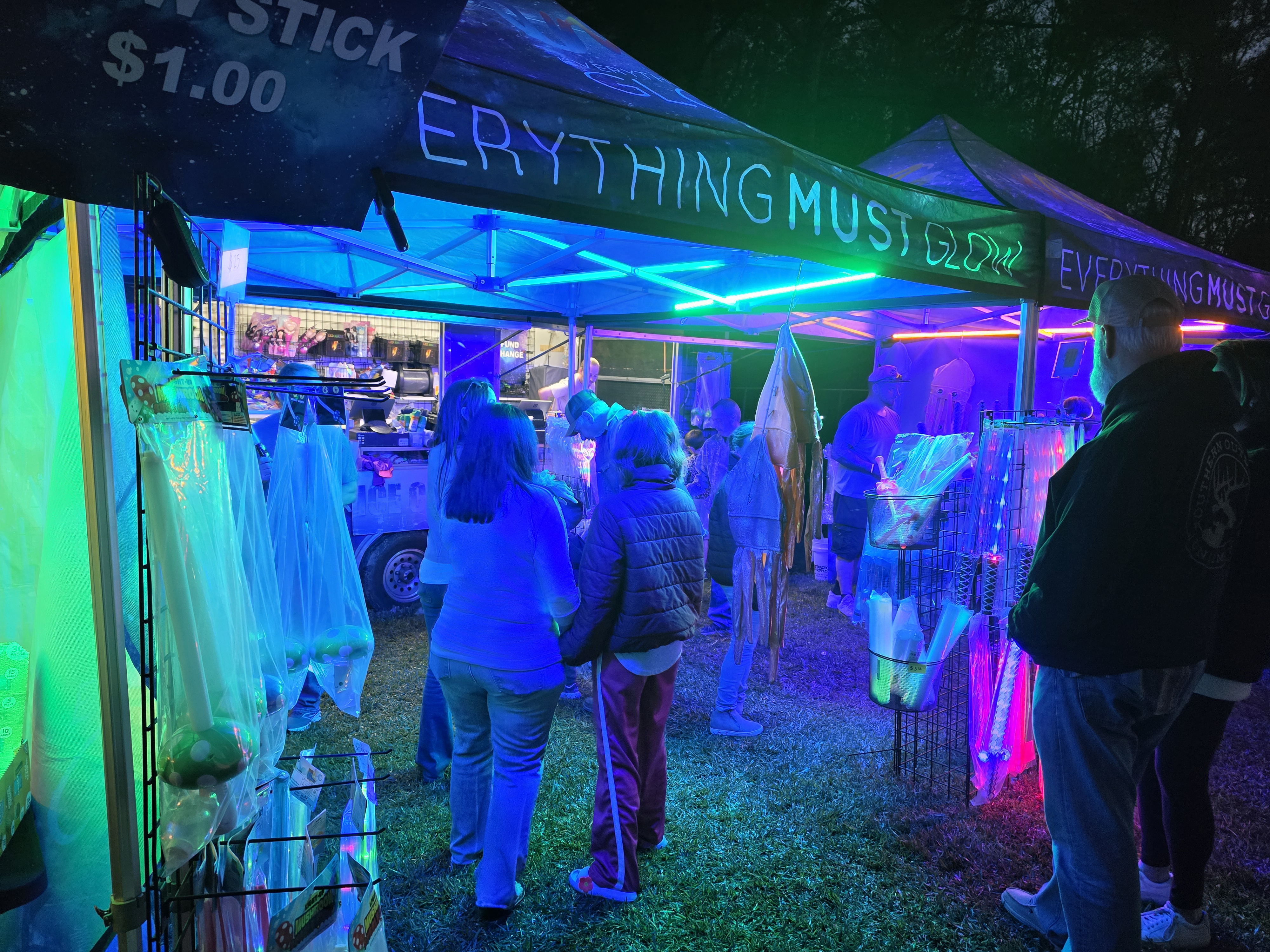 Pink, green, and blue lasers cutting through the night sky next to the booth